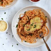 Crispy air fryer chicken parmesan with melted cheese on a bed of spaghetti.