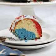 A slice of red, white and blue bundt cake with star sprinkles on dessert plate.
