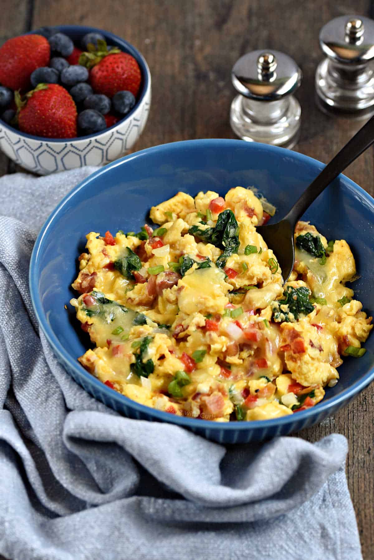 Scrambled eggs with bell pepper, onion, spinach and cheese in a serving bowl.