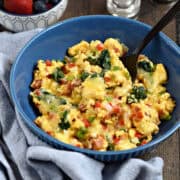 Scrambled eggs with bell pepper, onion, spinach and cheese in a serving bowl.