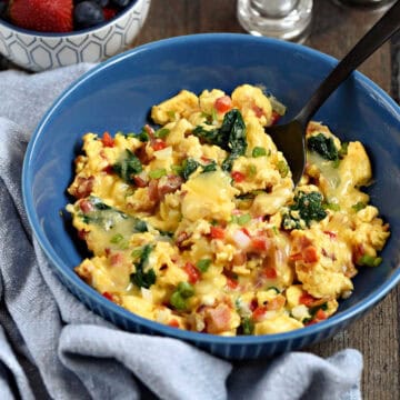 Scrambled eggs with bell pepper, onion, spinach and cheese in a serving bowl.