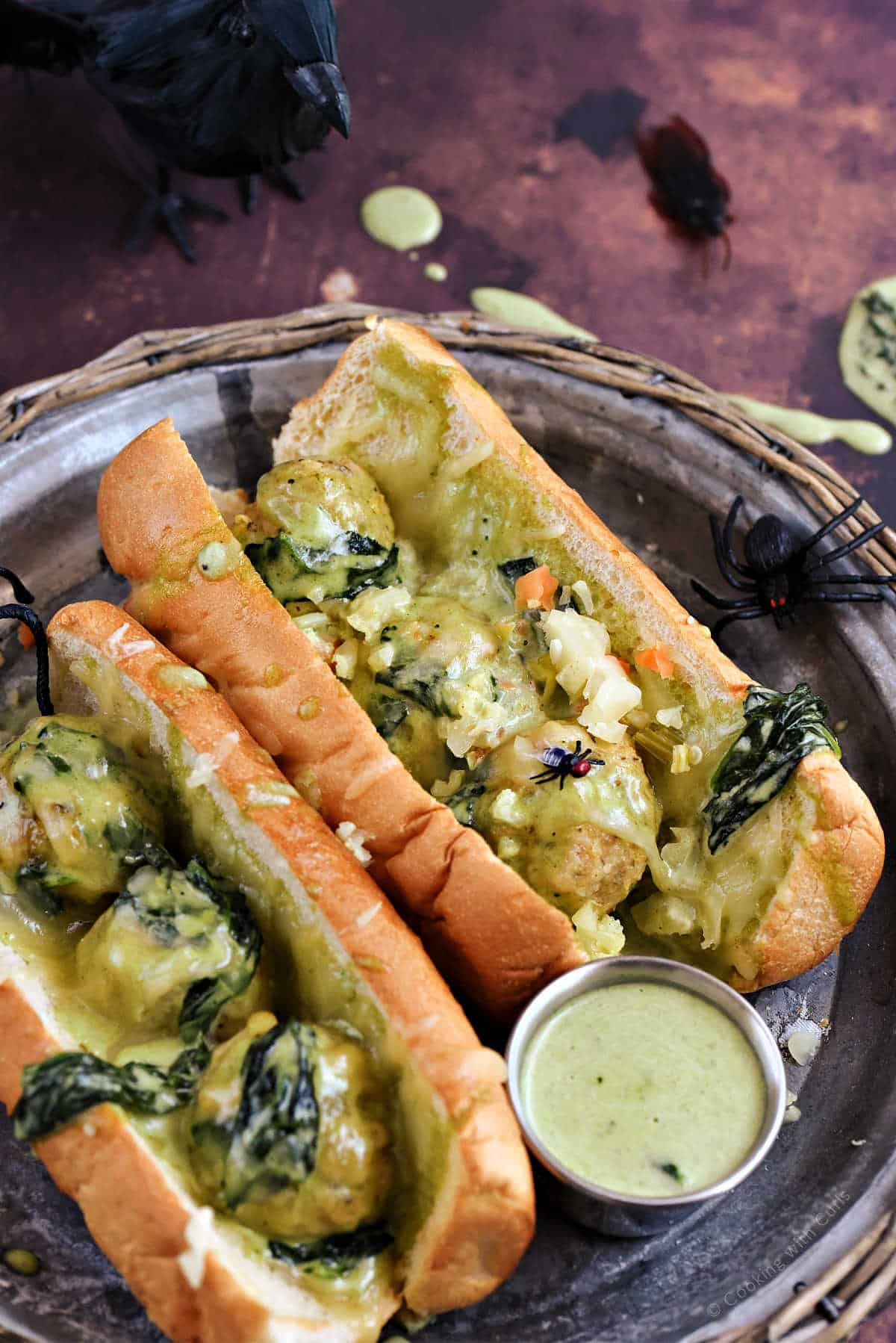 Chicken meatball sandwiches topped with Alfredo sauce, melted cheese, and wilted spinach.