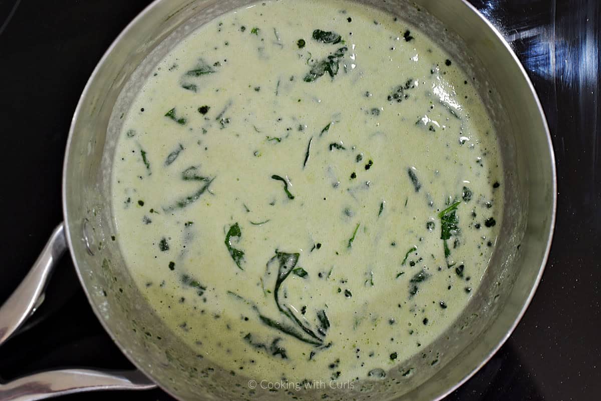 Green Alfredo sauce with spinach in sauce pan.