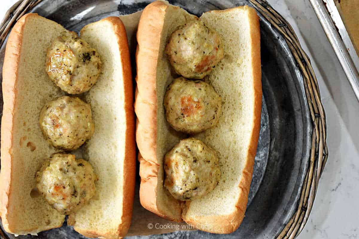 Two hoagie rolls with three chicken meatballs in each.
