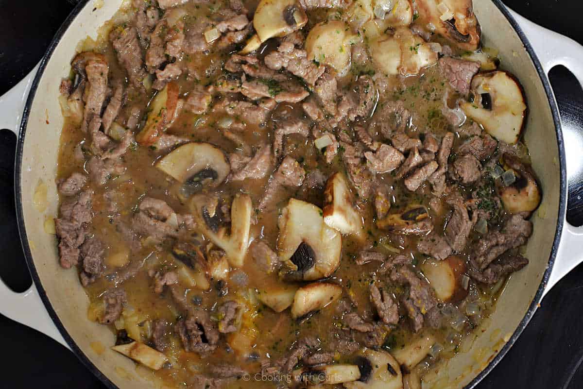 Beef strips, sliced mushrooms, and broth in skillet.
