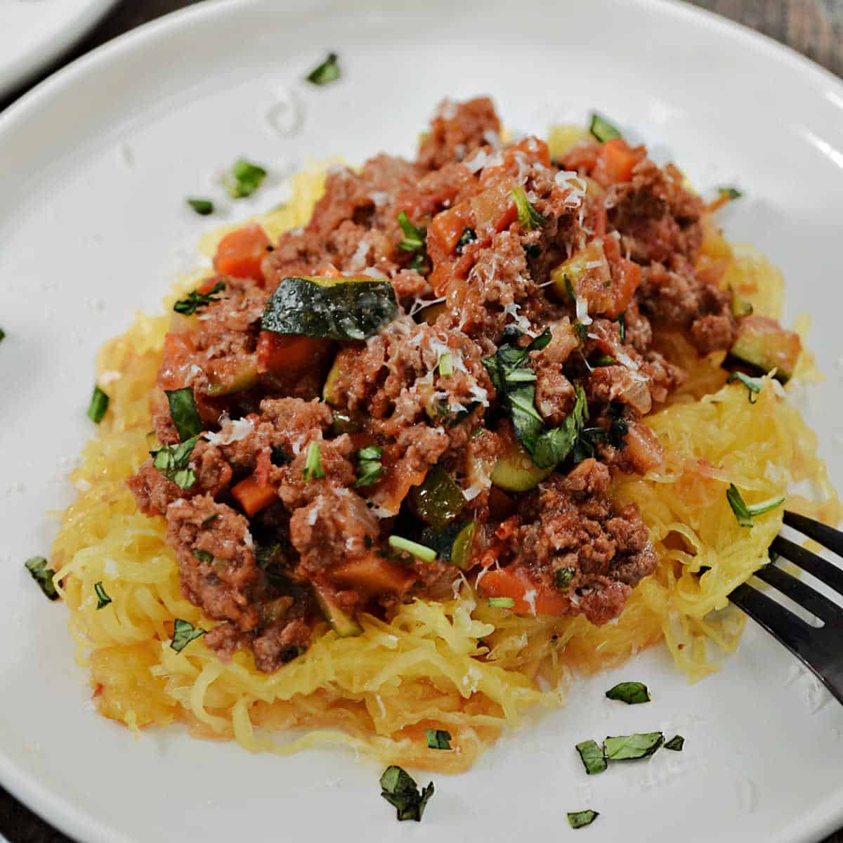 Spaghetti squash topped with meat sauce and chopped parsley.