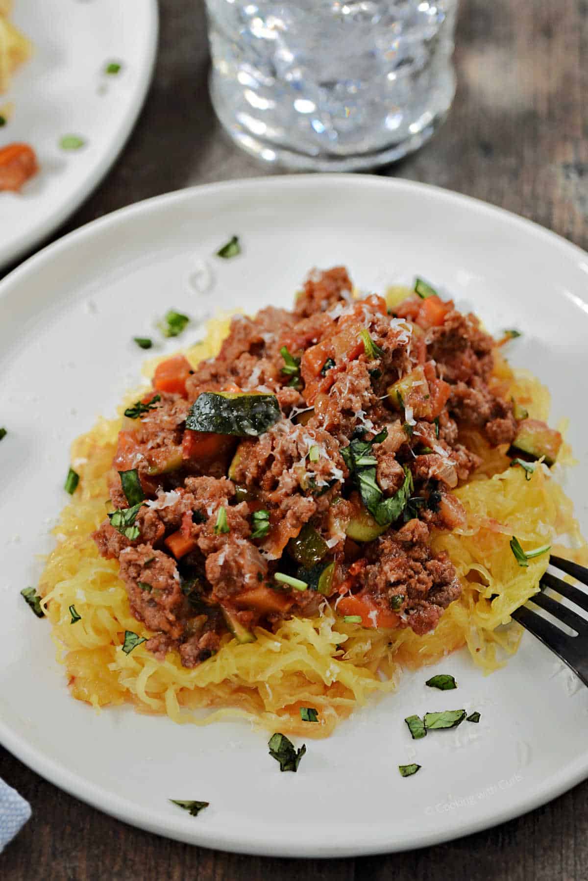 Spaghetti squash topped with meat sauce and chopped parsley.
