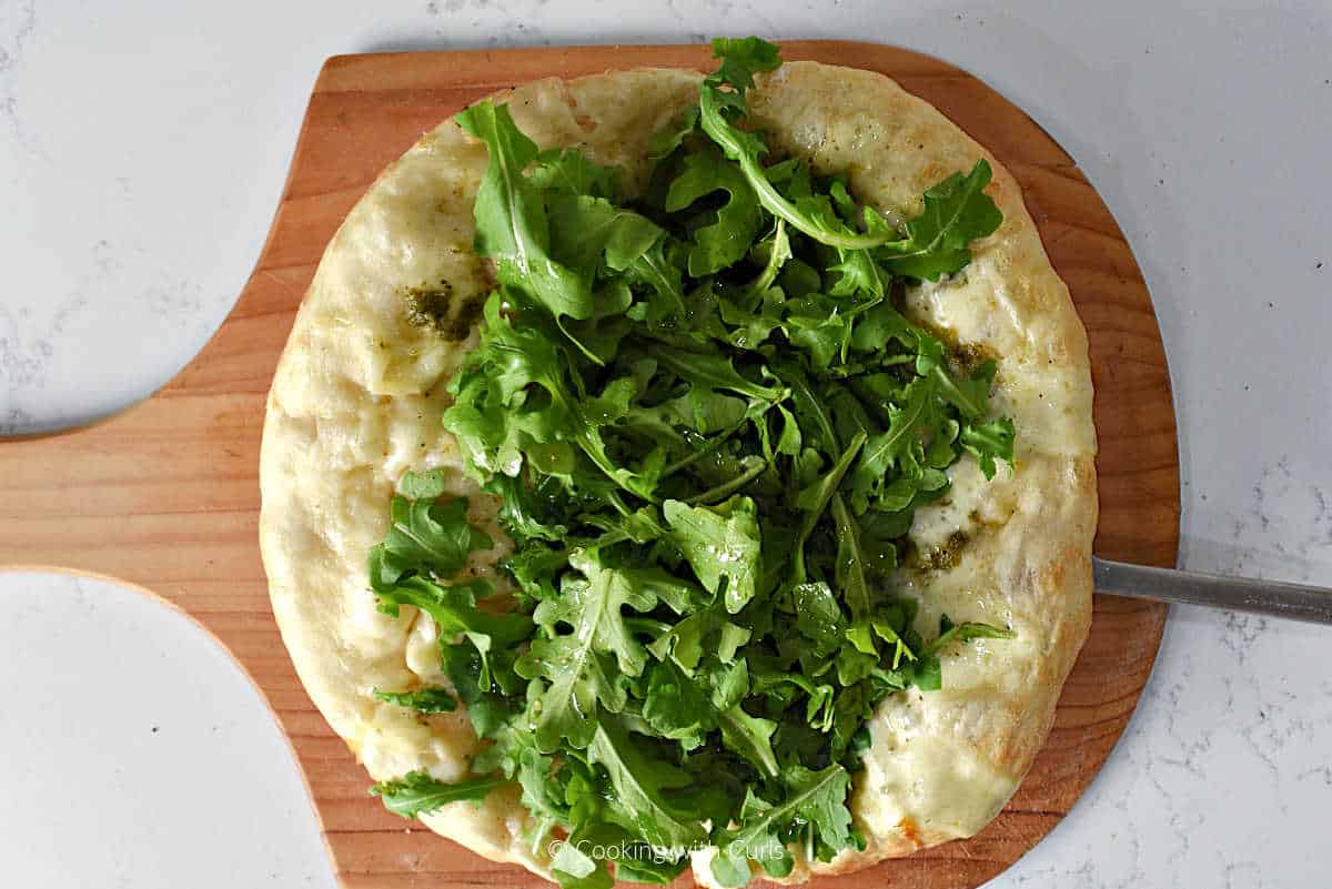 Arugula, pesto, and melted mozzarella on baked pizza crust.