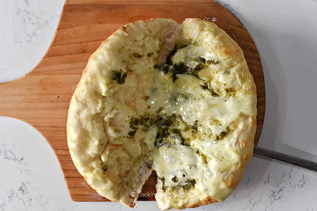 Melted mozzarella and pesto on baked pizza crust.