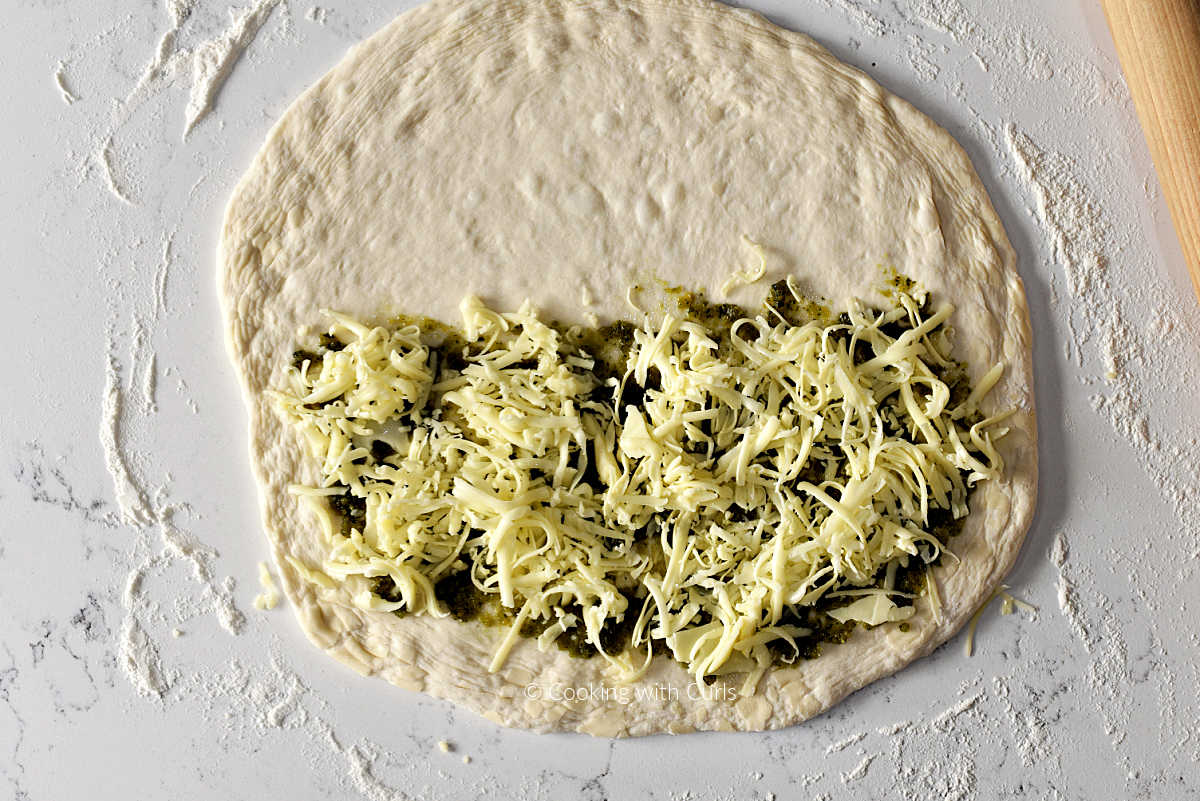 Pizza dough circle topped with pesto and mozzarella cheese.