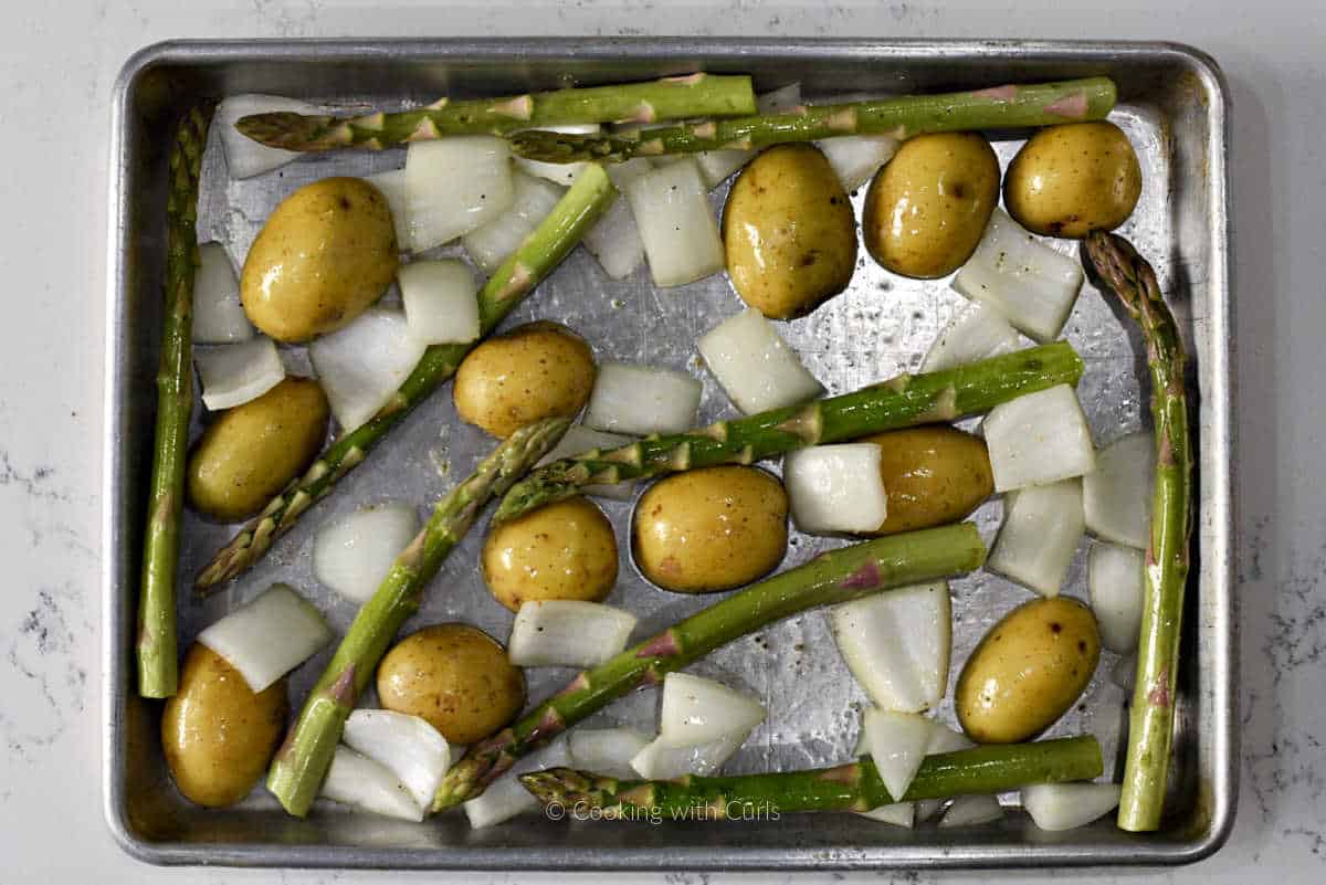 Potato halves, onion, and asparagus on sheet pan.