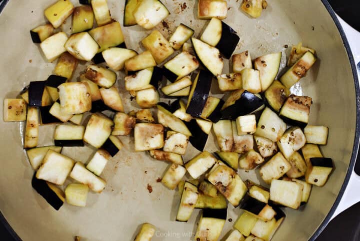 Chopped eggplant cooking in skillet.