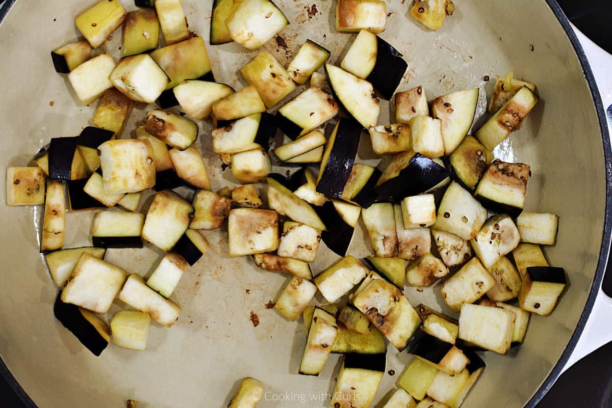 Chopped eggplant cooking in skillet.