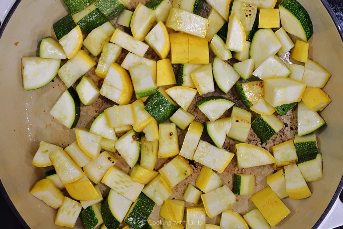 Chopped zucchini and squash cooking in a skillet.