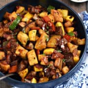 Chopped, cooked eggplant, squash, tomatoes, and red bell pepper in a bowl.